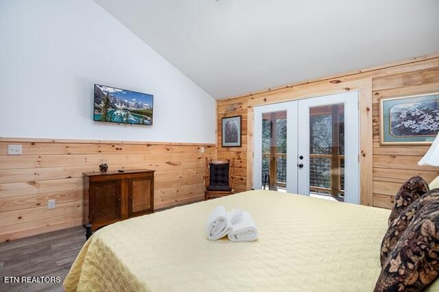 bedroom with access to outside, wooden walls, french doors, and lofted ceiling