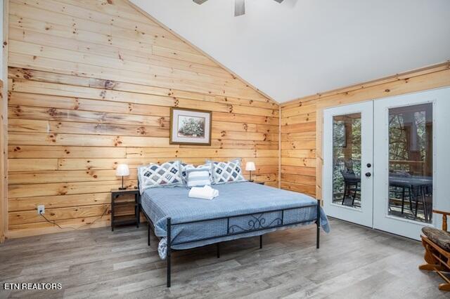 bedroom featuring access to exterior, wooden walls, french doors, and hardwood / wood-style flooring