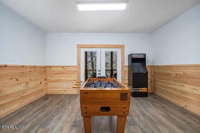 game room with wooden walls, french doors, and dark wood-type flooring