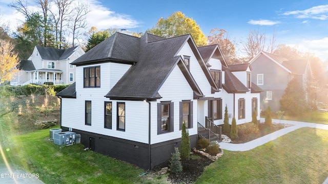 view of side of property with central AC and a lawn