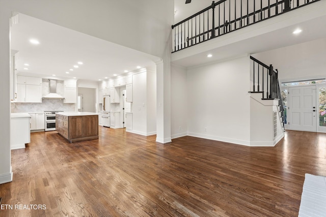 unfurnished living room featuring a high ceiling and dark wood-type flooring