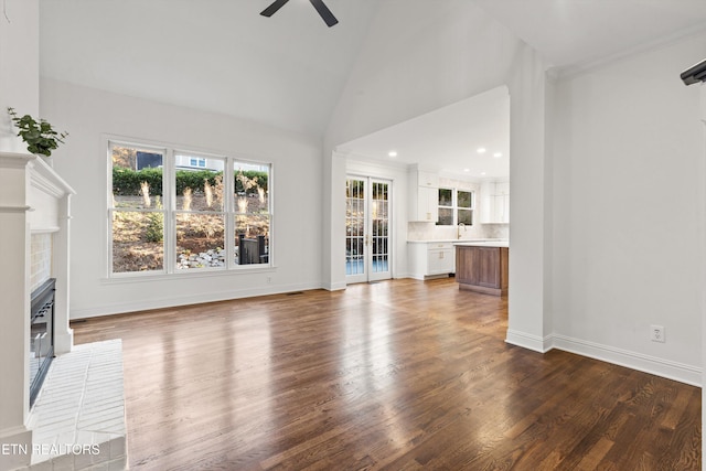 unfurnished living room with hardwood / wood-style flooring, high vaulted ceiling, ceiling fan, and sink