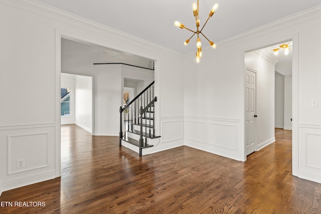 empty room featuring crown molding, dark hardwood / wood-style flooring, and a notable chandelier