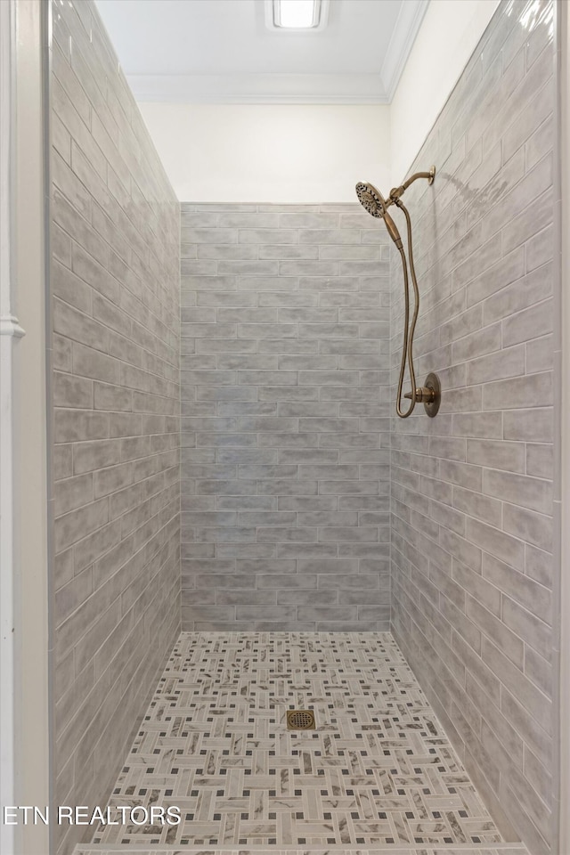 bathroom with a tile shower and crown molding