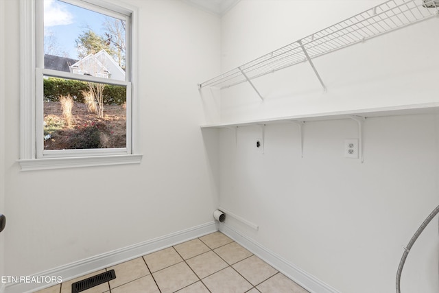 clothes washing area featuring hookup for an electric dryer, light tile patterned floors, and a wealth of natural light