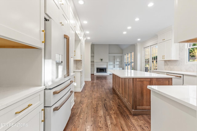 kitchen with backsplash, white appliances, white cabinetry, dark hardwood / wood-style floors, and a kitchen island