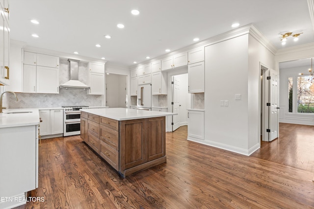 kitchen with white cabinets, dark hardwood / wood-style flooring, wall chimney exhaust hood, and stainless steel range oven