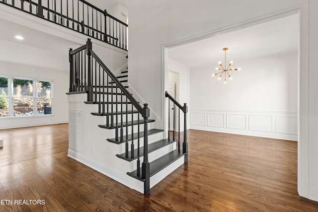 stairway featuring crown molding, wood-type flooring, and a notable chandelier