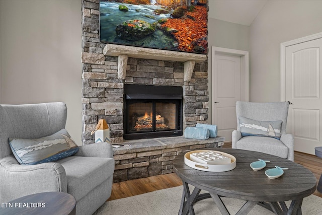 sitting room with wood-type flooring, vaulted ceiling, and a fireplace