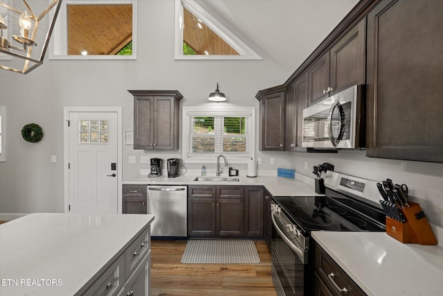 kitchen with appliances with stainless steel finishes, dark brown cabinetry, dark hardwood / wood-style flooring, sink, and vaulted ceiling