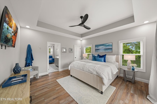 bedroom with multiple windows, wood-type flooring, ceiling fan, and ensuite bathroom