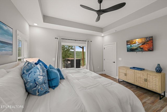 bedroom featuring ceiling fan, access to exterior, dark hardwood / wood-style floors, and a raised ceiling