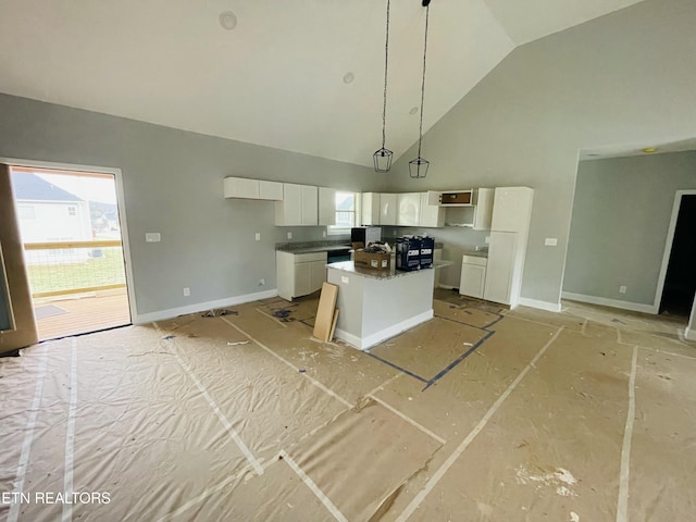 kitchen with high vaulted ceiling, white cabinetry, a kitchen island, and baseboards