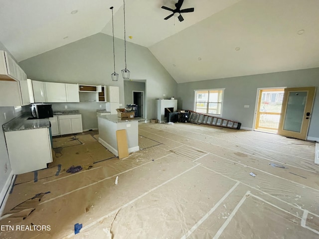 kitchen featuring high vaulted ceiling, a kitchen island, white cabinets, open floor plan, and decorative light fixtures