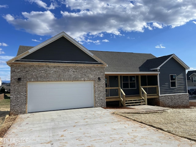 ranch-style home with covered porch, a garage, brick siding, driveway, and roof with shingles