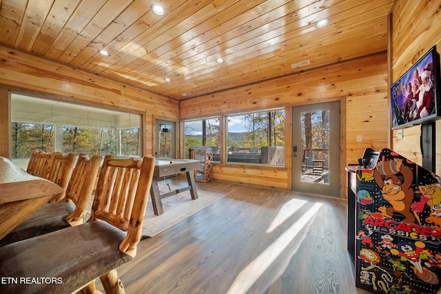 dining area with hardwood / wood-style floors, wooden ceiling, and wood walls