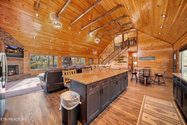 kitchen with light stone counters, high vaulted ceiling, wooden walls, wood ceiling, and light wood-type flooring