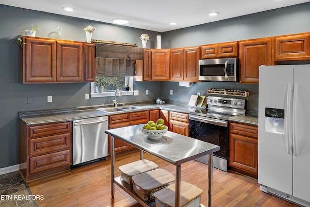 kitchen with stainless steel appliances, light hardwood / wood-style floors, and sink