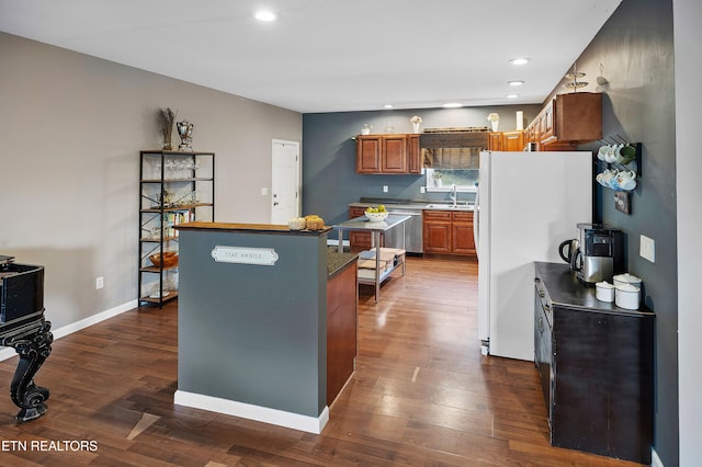 kitchen featuring white refrigerator, sink, dark wood-type flooring, and a kitchen island