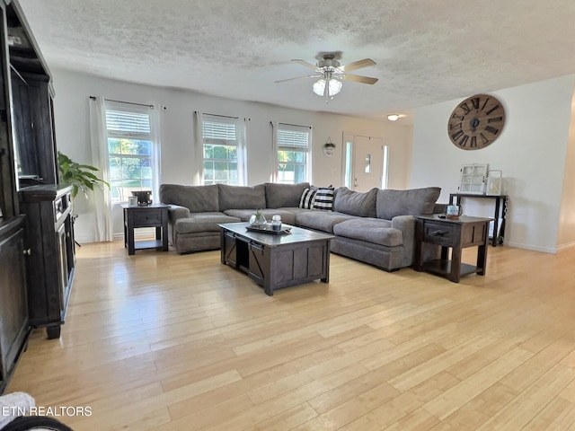 living room featuring ceiling fan, light hardwood / wood-style floors, and a textured ceiling