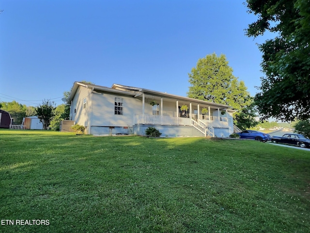 view of front of home featuring covered porch, a storage unit, and a front lawn