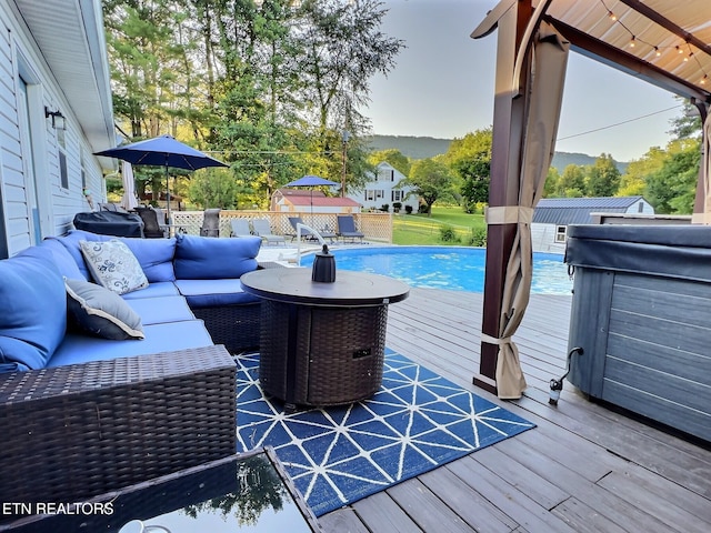 wooden terrace with an outdoor living space and a swimming pool with hot tub