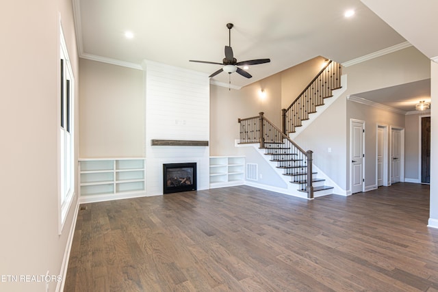 unfurnished living room with ceiling fan, a large fireplace, dark hardwood / wood-style floors, and ornamental molding