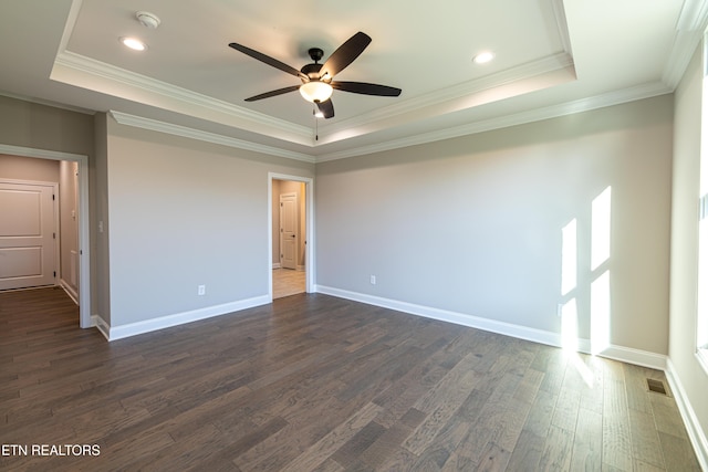 empty room featuring a raised ceiling, crown molding, ceiling fan, and dark wood-type flooring