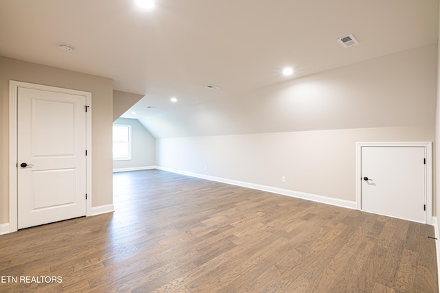 additional living space featuring hardwood / wood-style flooring and vaulted ceiling