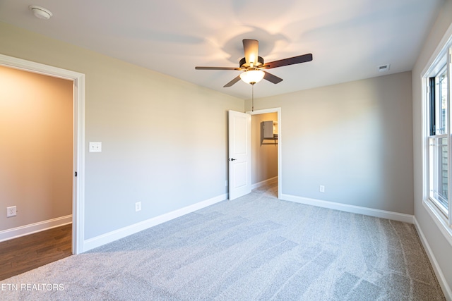 spare room featuring dark colored carpet and ceiling fan