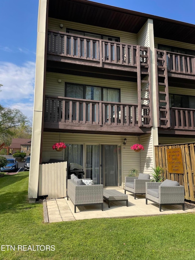 back of property with a yard, a patio, and a balcony