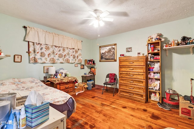 bedroom with ceiling fan, wood-type flooring, and a textured ceiling