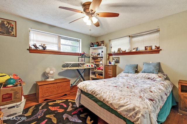 bedroom with a textured ceiling, dark hardwood / wood-style flooring, and ceiling fan