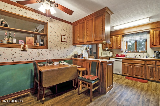 kitchen featuring ceiling fan, stainless steel dishwasher, dark hardwood / wood-style floors, kitchen peninsula, and ornamental molding