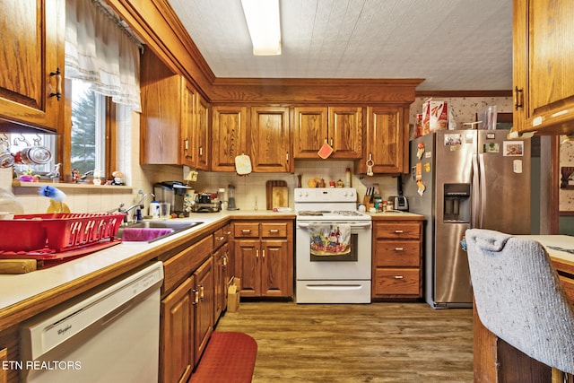 kitchen featuring decorative backsplash, white appliances, crown molding, dark wood-type flooring, and sink