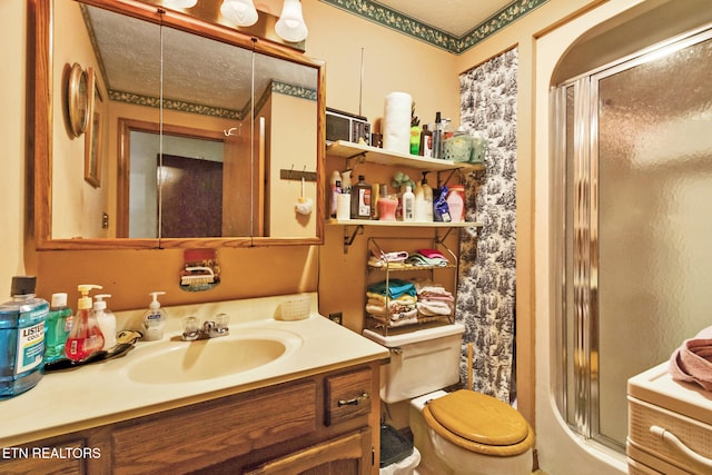 bathroom with a shower with door, vanity, a textured ceiling, and toilet