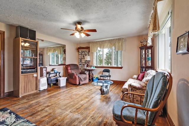 living room featuring wood-type flooring, a textured ceiling, and ceiling fan