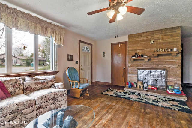 living room with a textured ceiling, ceiling fan, and dark wood-type flooring