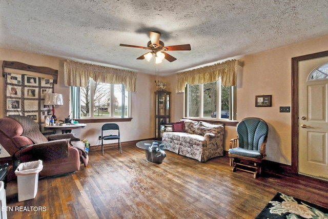 living room featuring dark hardwood / wood-style floors, ceiling fan, and a textured ceiling