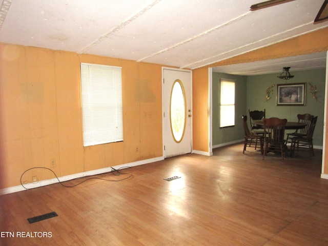 foyer entrance featuring wood walls, hardwood / wood-style flooring, and lofted ceiling