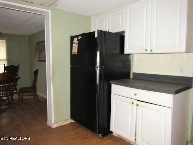 kitchen featuring white cabinetry, black fridge, and dark hardwood / wood-style floors