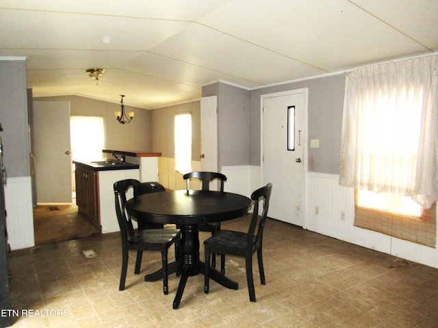 dining room featuring an inviting chandelier, lofted ceiling, and sink