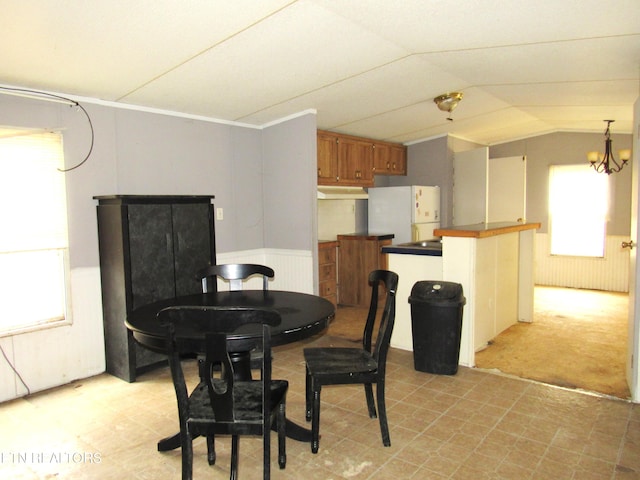 dining area with light colored carpet, lofted ceiling, and a notable chandelier