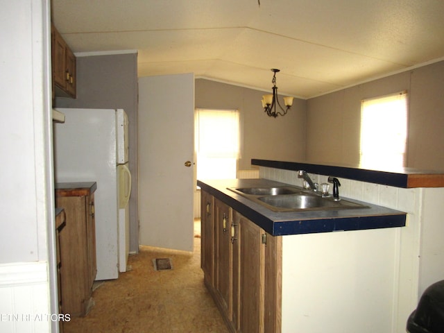 kitchen with white refrigerator, sink, vaulted ceiling, hanging light fixtures, and a chandelier