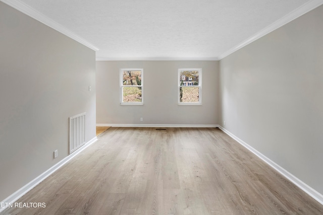 empty room with a textured ceiling, light wood-type flooring, and ornamental molding