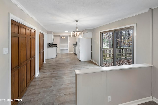 kitchen featuring white cabinets, hanging light fixtures, white fridge, and light hardwood / wood-style floors