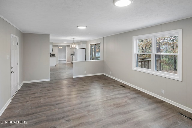 unfurnished room with a textured ceiling, dark wood-type flooring, and an inviting chandelier