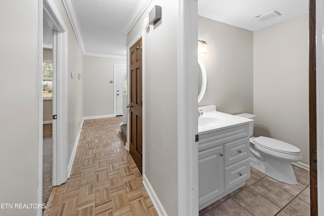 bathroom featuring parquet floors, ornamental molding, a textured ceiling, vanity, and toilet