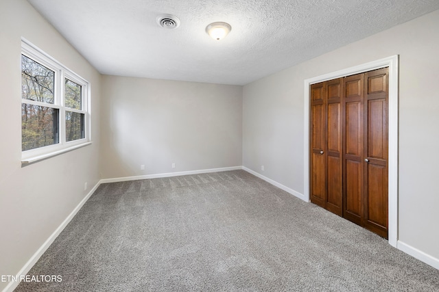 unfurnished bedroom featuring carpet flooring, a textured ceiling, and a closet