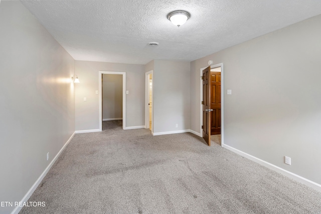 carpeted empty room with a textured ceiling